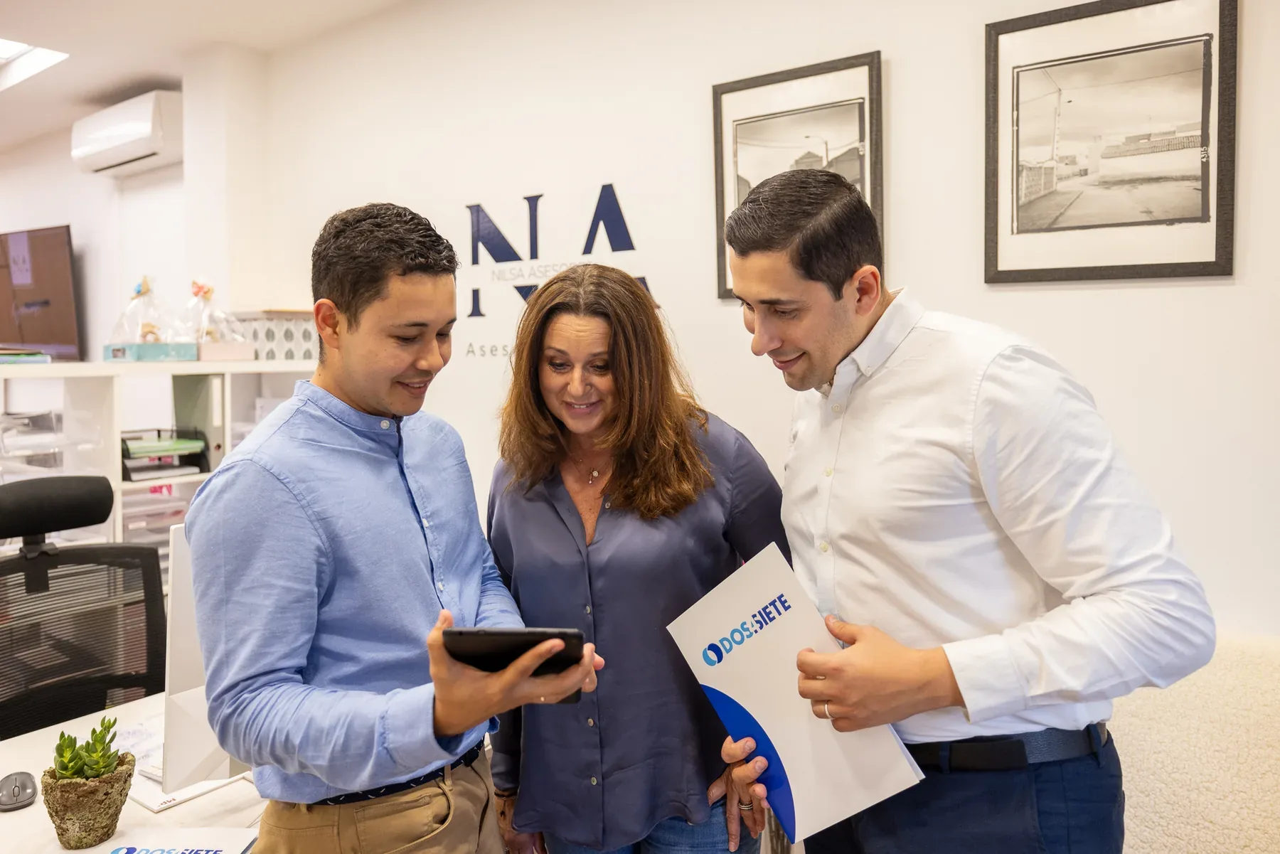 Tres personas consultan una tableta en una oficina.